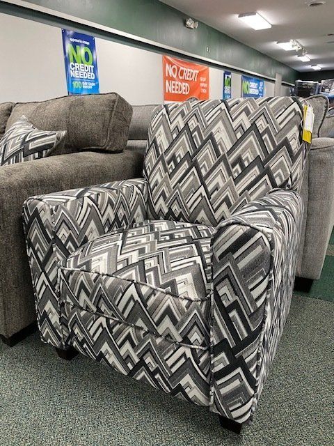 Upholstered armchair with a geometric black, gray, and white pattern, in a furniture store.