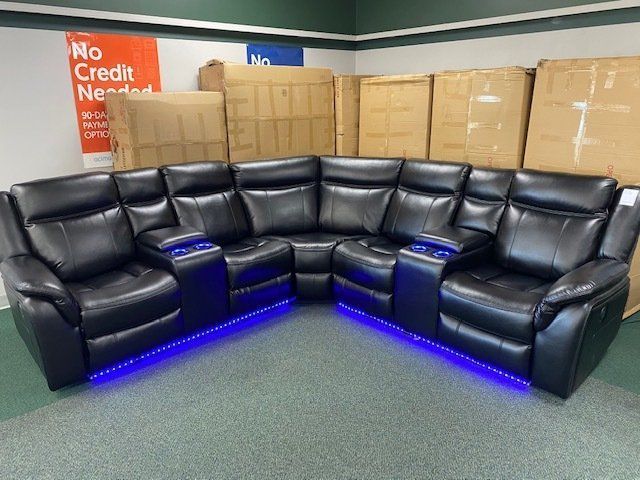 Black leather sectional sofa with blue LED lights in a store.
