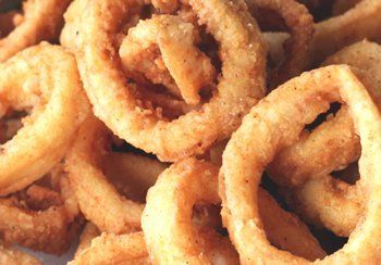 Close-up of golden-brown, deep-fried onion rings piled together.
