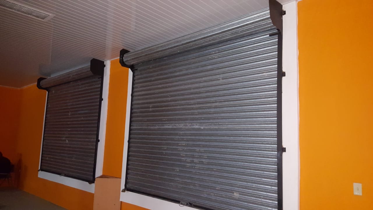 Dos persianas grises cerradas sobre una pared de color naranja brillante en una habitación.
