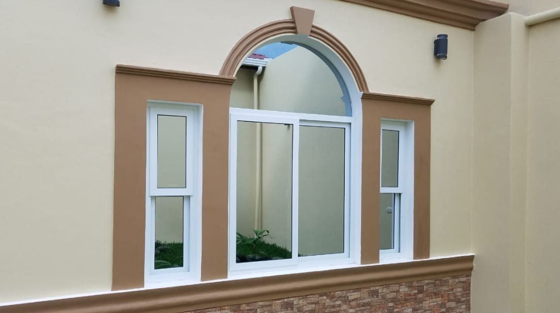 Fachada de edificio de color crema con una ventana central arqueada y ventanas laterales estrechas