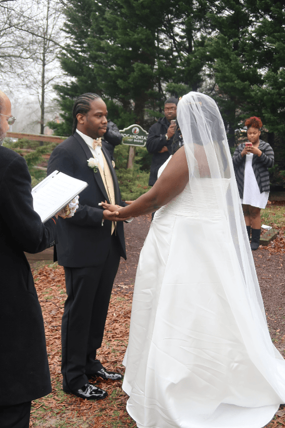 A bride and groom are holding hands during their wedding ceremony