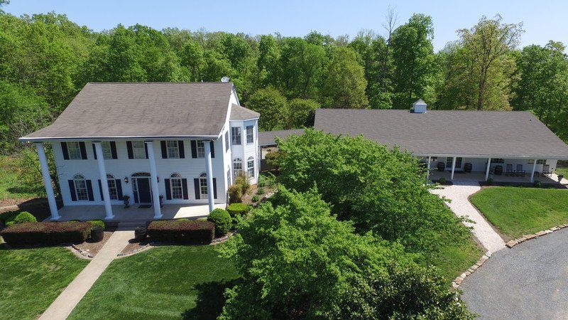 An aerial view of a large white house surrounded by trees