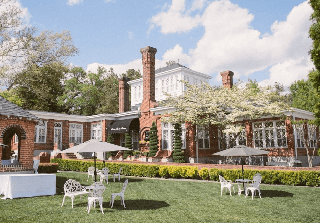A large brick building with tables and chairs in front of it.