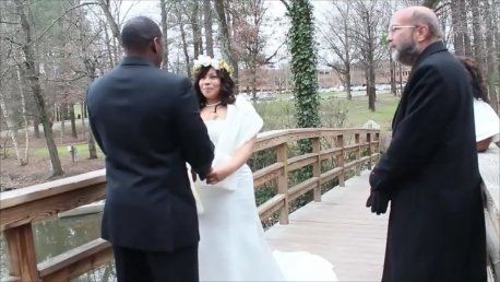 A bride and groom are holding hands on a wooden bridge