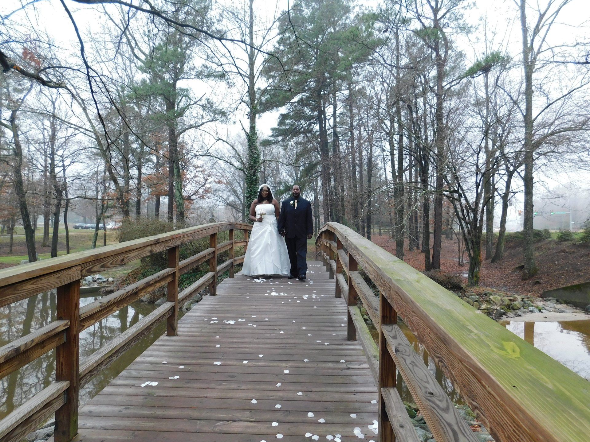 A bride and groom are standing on a wooden bridge.fffffffffffffff