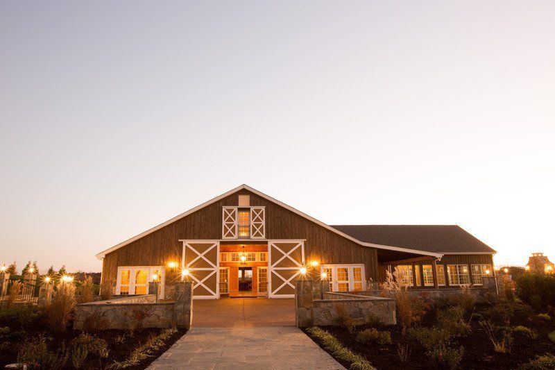 A large barn with a walkway leading to it is lit up at night.