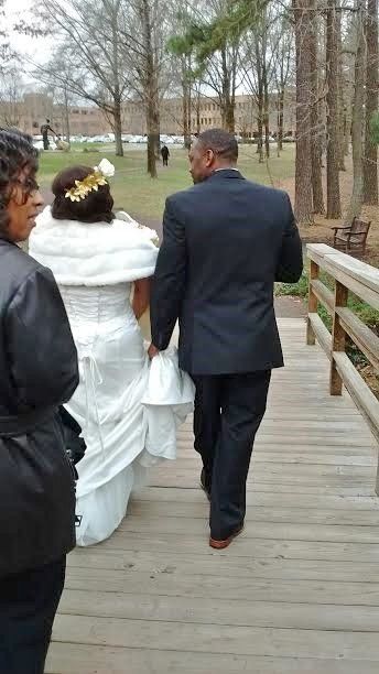 A bride and groom are walking down a wooden bridge.