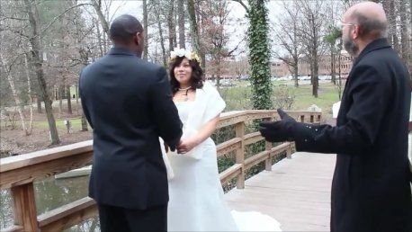 A bride and groom are holding hands on a wooden bridge