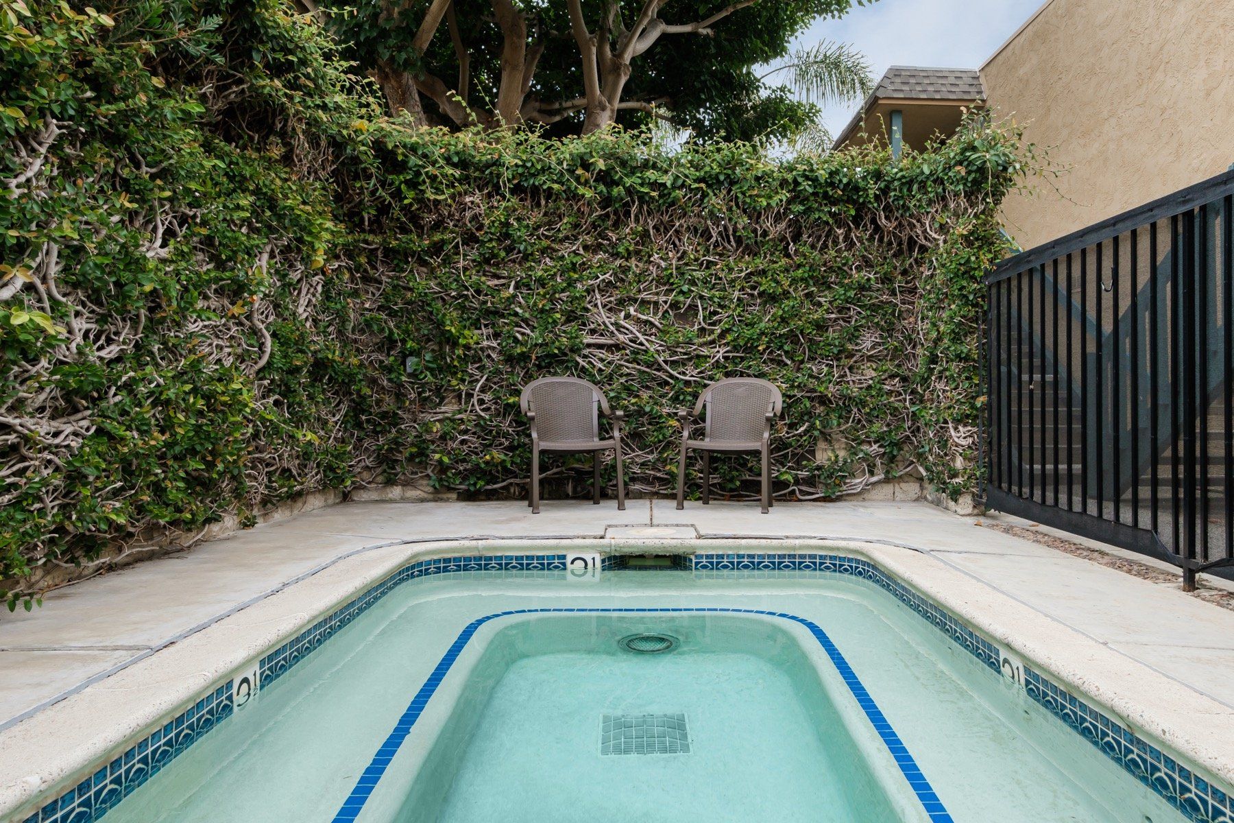 A small swimming pool with two chairs in front of it