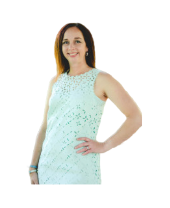 A smiling person poses in a light green, sleeveless dress with an intricate cut-out pattern against a white background.
