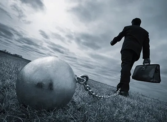 Business man with ball and chain around his ankle