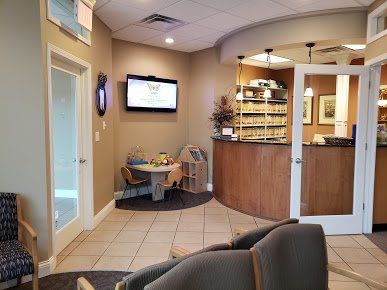 Hospital waiting area with TV, reception desk, chairs, and tiled floor