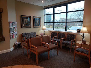 Quiet waiting room with orange chairs, table lamps, framed art, and large windows overlooking a snowy view