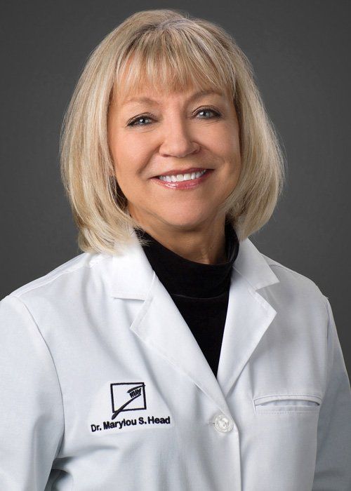 Smiling doctor in a white coat against a gray background