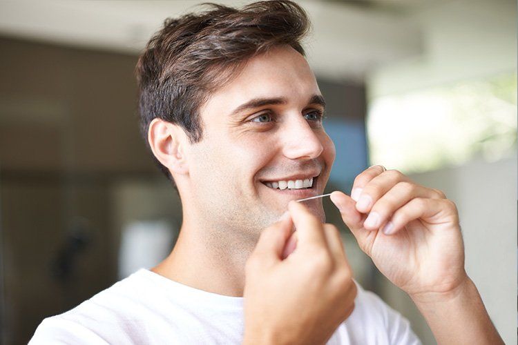 Smiling man adjusting clear aligners in a bright room