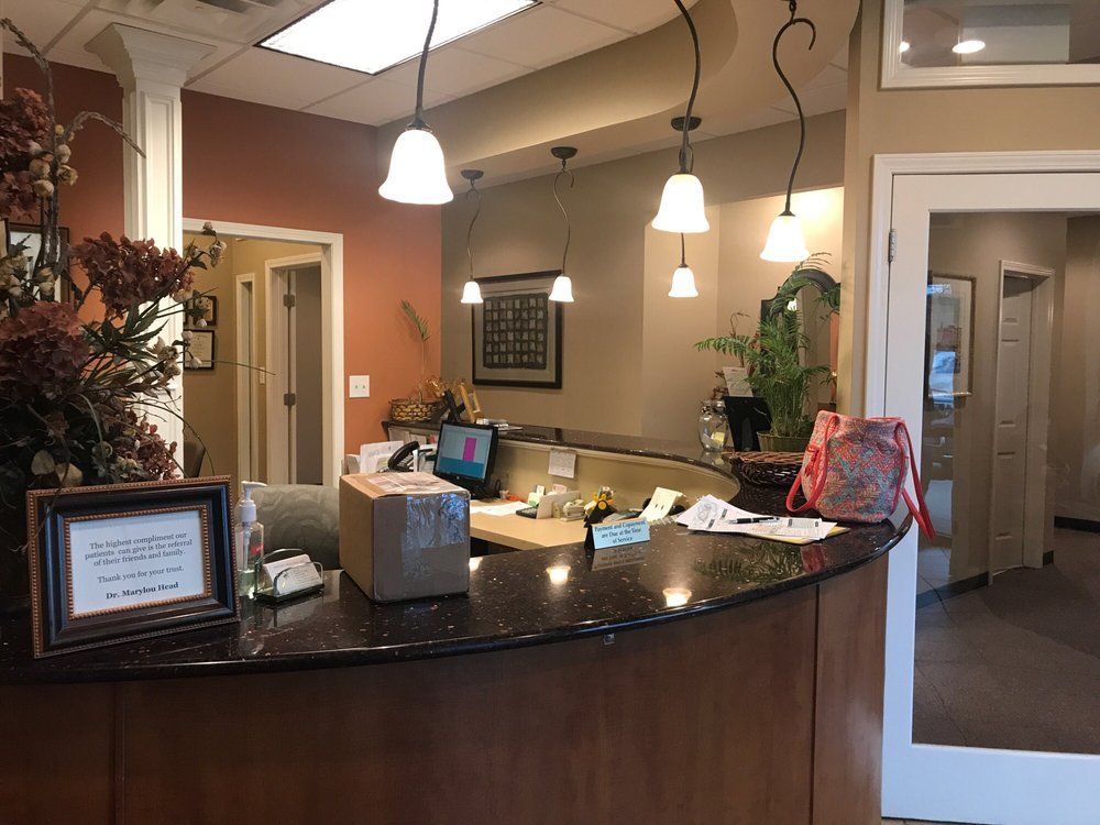 Hotel reception desk with pendant lights, framed sign, and hallway visible in the background