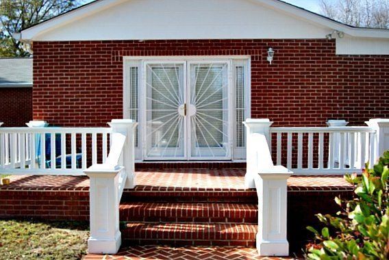a brick house with a white railing and sliding glass doors