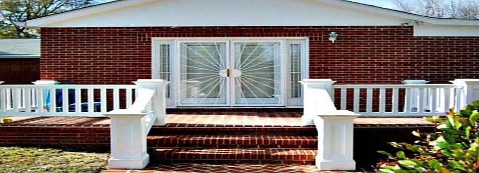 a brick house with a white railing and stairs