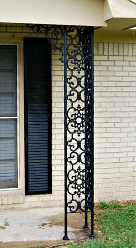 a white brick house with black shutters and a wrought iron porch