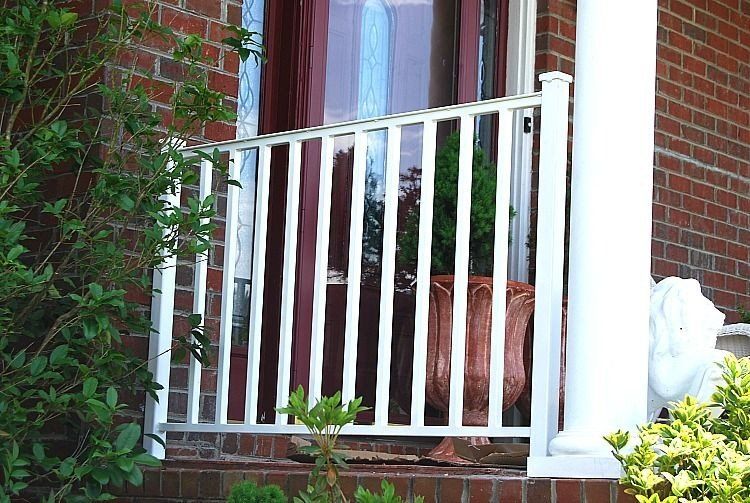 a porch with a white railing and a potted plant on it .