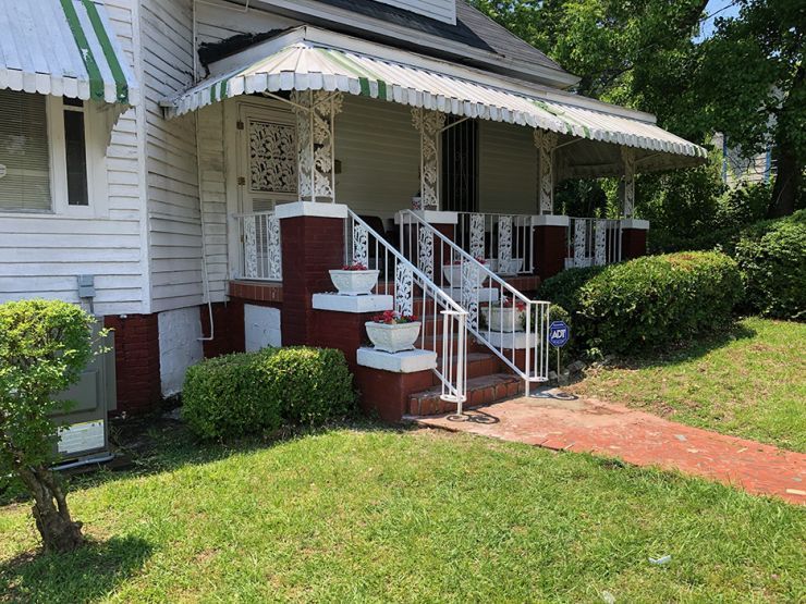 a white house with a green and white awning over the porch .