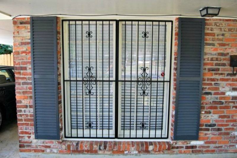 a brick building with shutters and a wrought iron gate