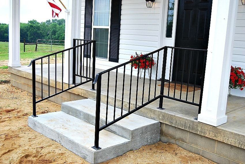 a white house with a black door and a black railing on the porch .