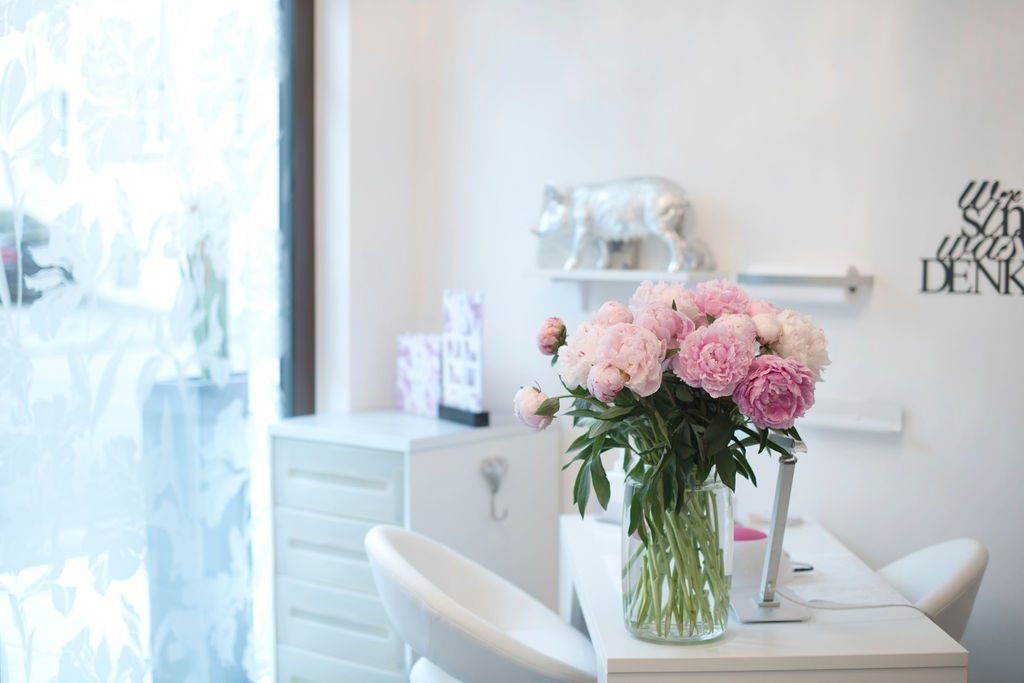 Helles Studio mit rosa Blumen in einer Vase auf einem weißen Tisch am Fenster