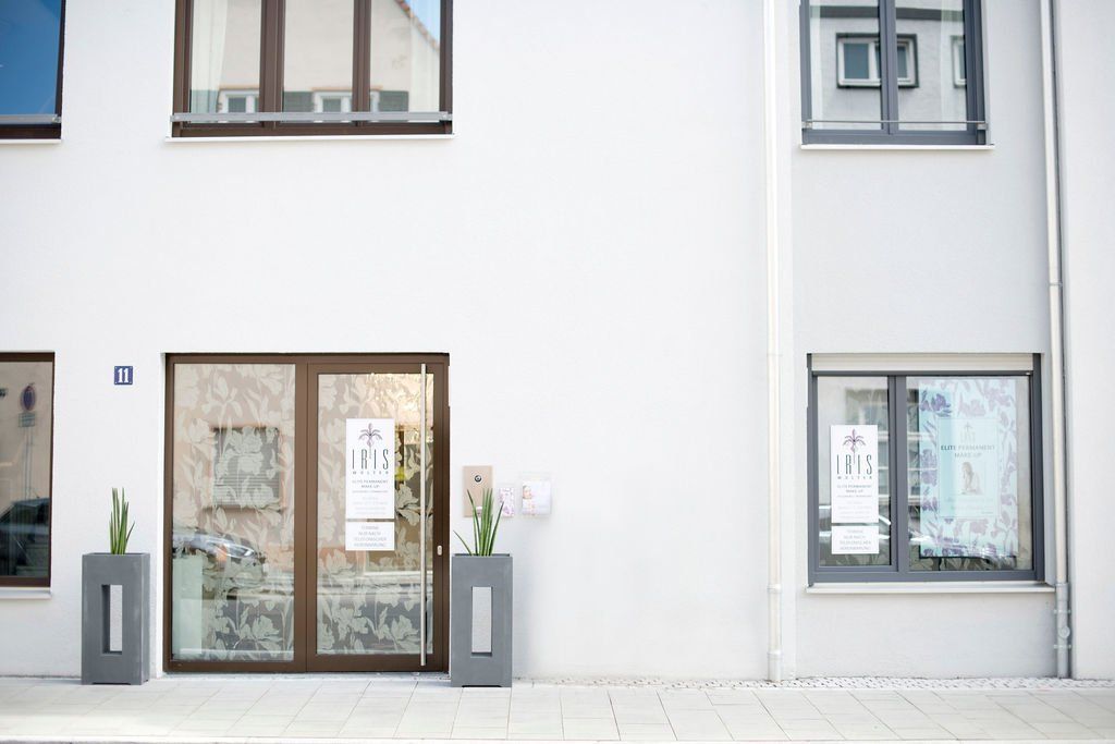 Moderne weiße Fassade eines Mehrfamilienhauses mit Eingangstüren zum Elite Permanent Make-Up Studio von Iris Wolter