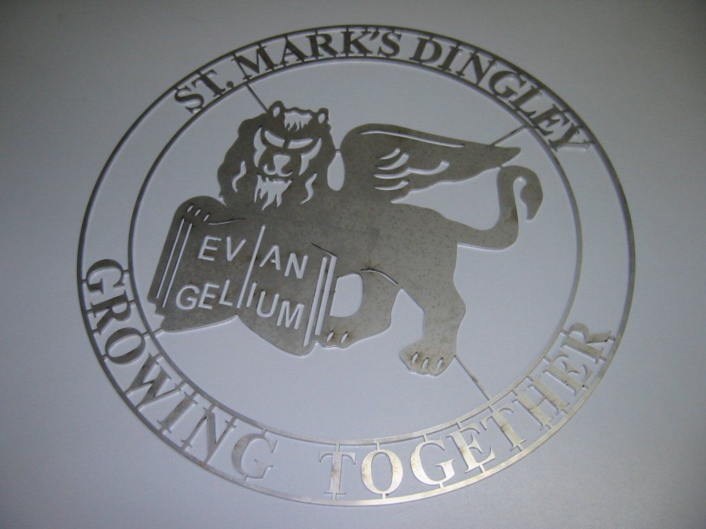 Metal emblem of St. Mark's Dingley. A winged lion holds a book labeled 