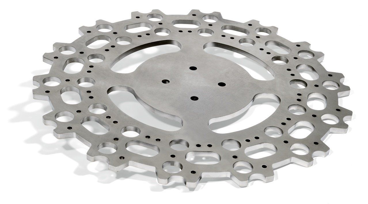 Silver metal bicycle cassette with cut-out holes and teeth, casting a shadow.