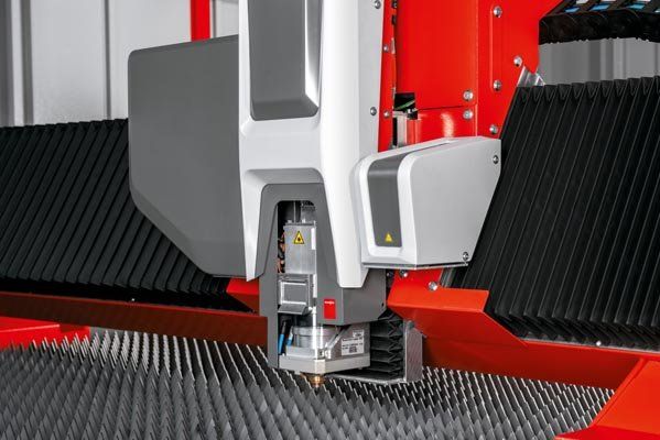 Close-up of a laser cutting machine in operation, focused on the cutting head. Red, gray and black color scheme.