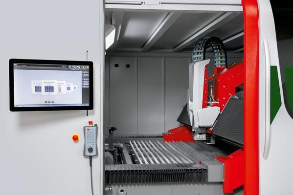 CNC milling machine interior with a control screen, red and white machinery, and a metal table.