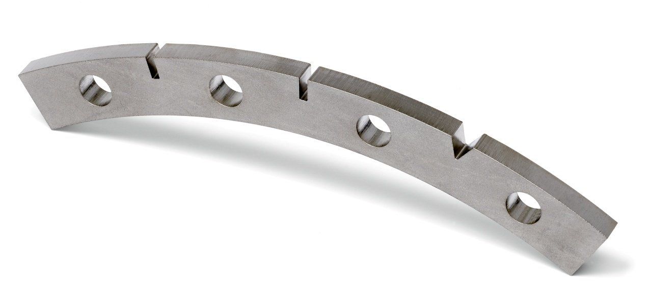 Curved metal plate with several holes and notches, likely a mechanical component.