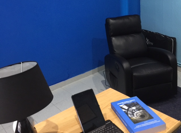 Un libro azul está sobre una mesa al lado de una computadora portátil.