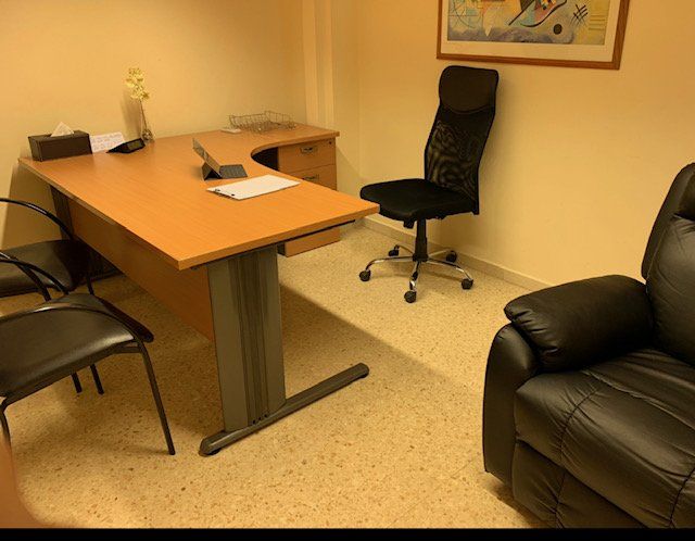 Una habitación con una silla de escritorio y un sofá