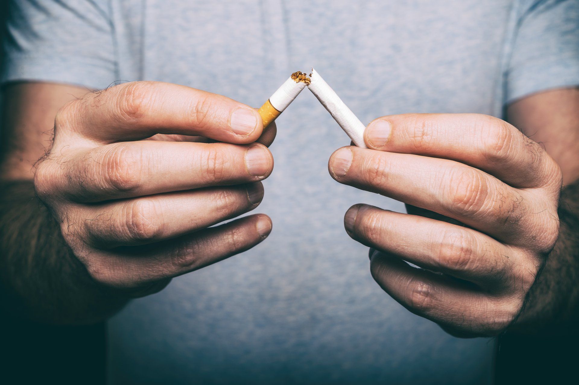 Un hombre sostiene dos cigarrillos rotos en sus manos.