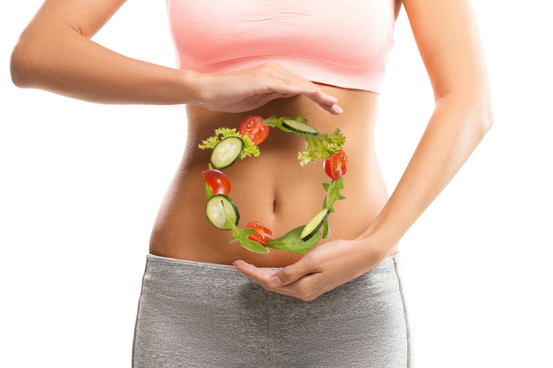 Una mujer sostiene una corona de verduras sobre su estómago.