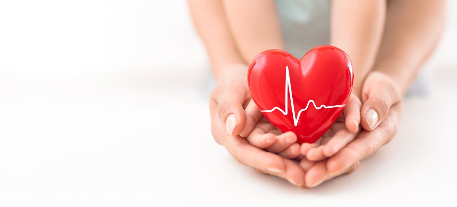 A woman and child are holding a red heart in their hands.