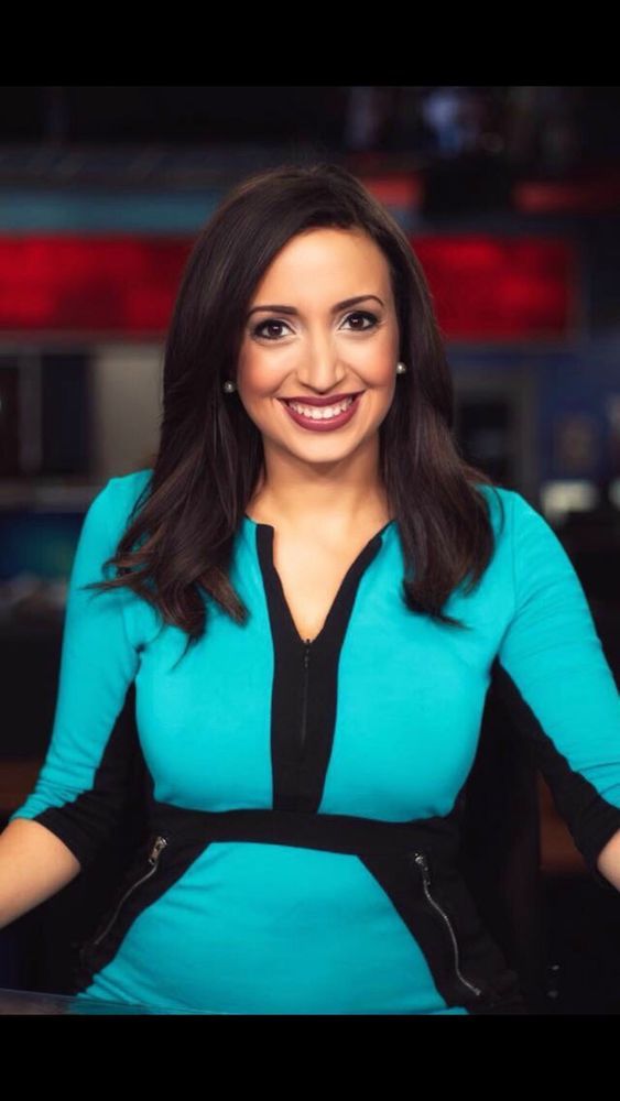 A woman in a blue dress is smiling for the camera.
