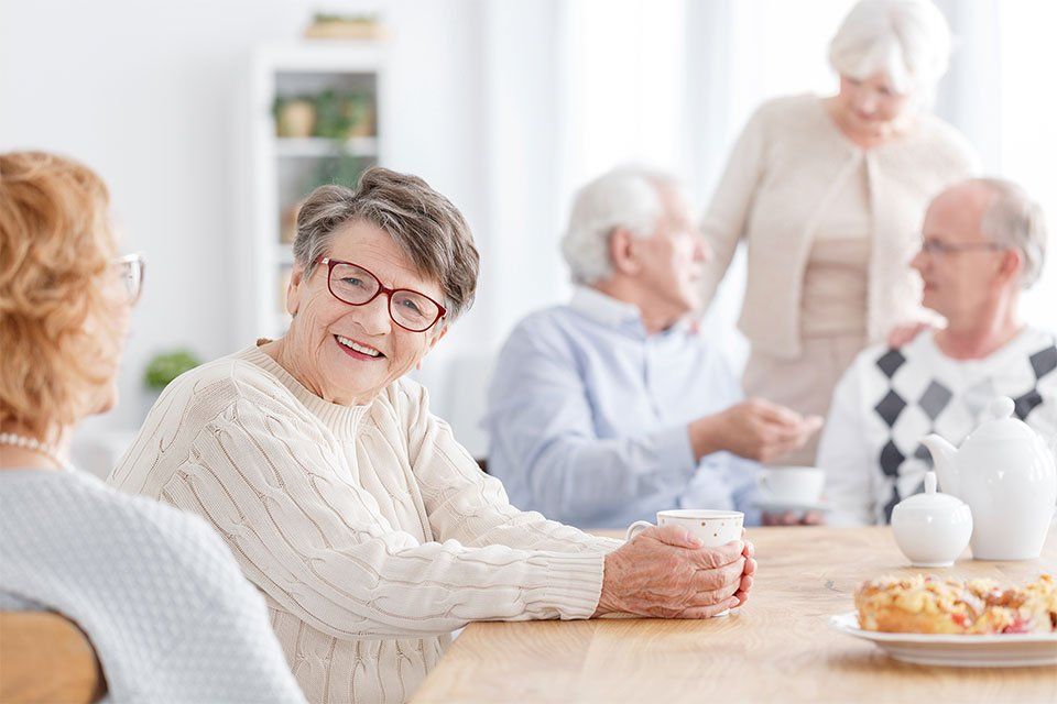 smiling old lady in a care home holding a coffee cup