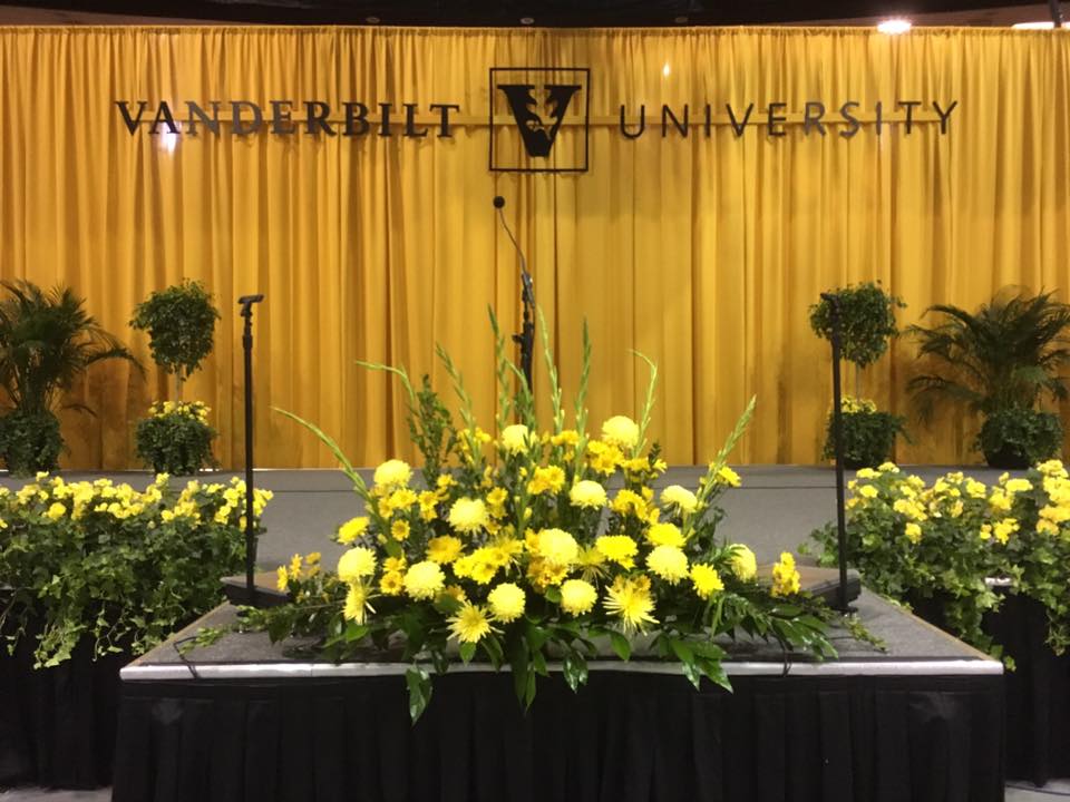 a stage with yellow flowers in front of a yellow curtain that says vanderbilt university