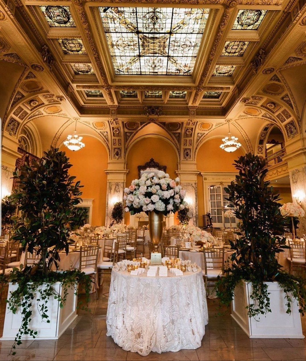 a table with flowers on it in a room with a stained glass ceiling
