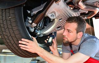 Auto Air Conditioning Service — Mechanic Inspecting The Car Tire in Kennett Square, PA Auto Air Conditioning Service — Mechanic Inspecting The Car Tire in Kennett Square, PA