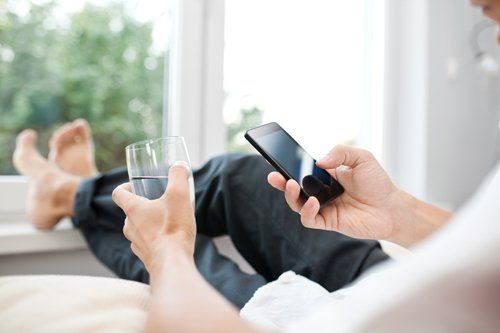 Man holding his Phone with a glass of water