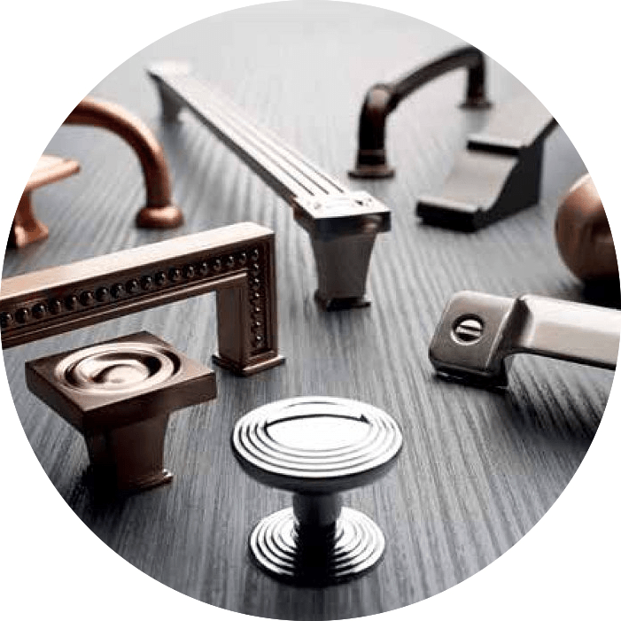 A variety of cabinet handles and knobs are sitting on a wooden table.