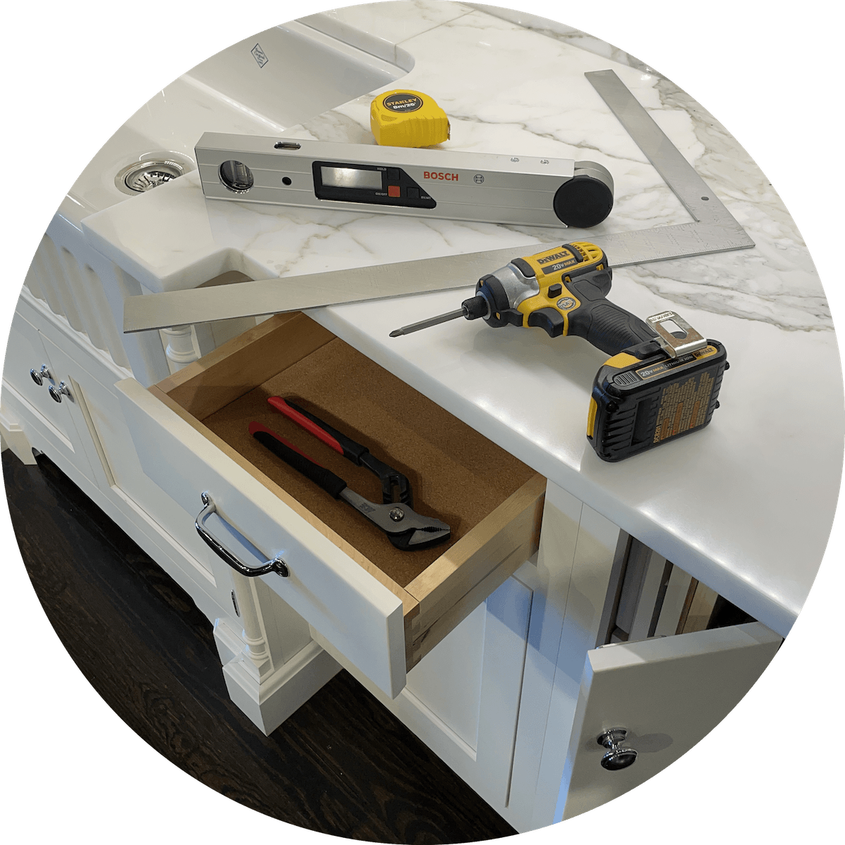 A drill is sitting on a counter next to a level and a tape measure.