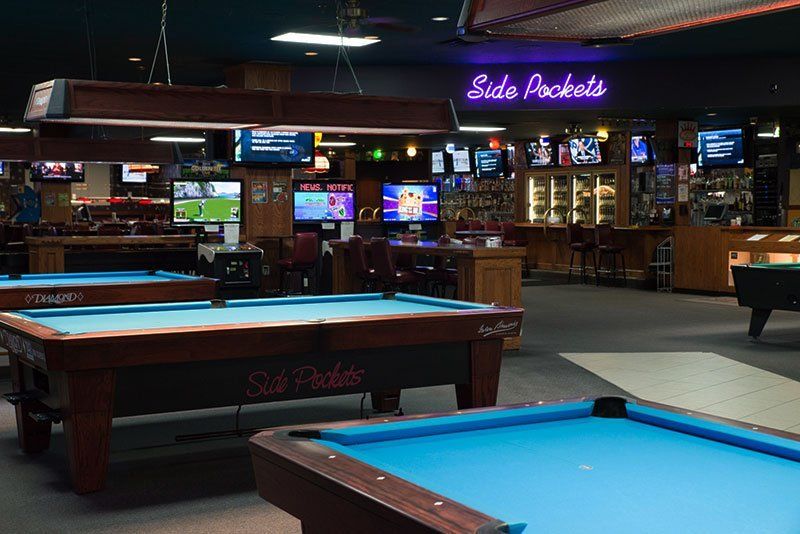 Pool hall interior with, a bar, and TVs. Sign says 