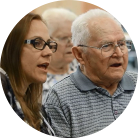 A woman and an older man are singing together in a circle